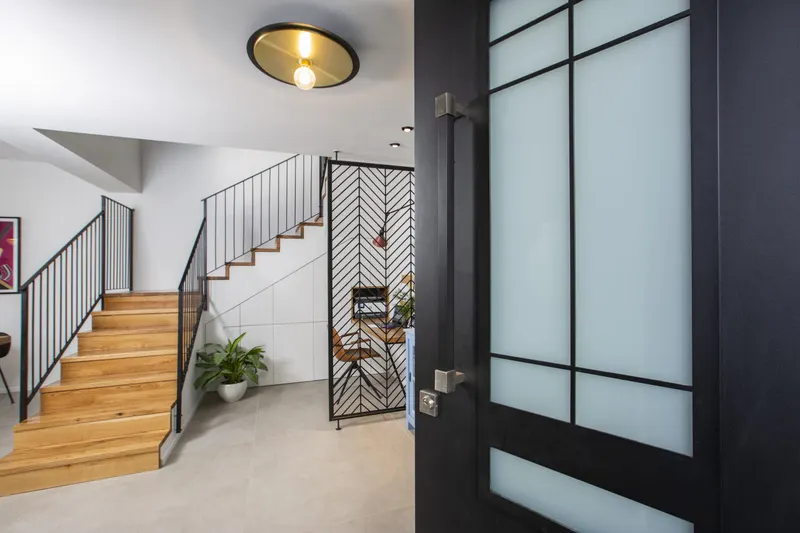 Black glazed door beside a wooden staircase